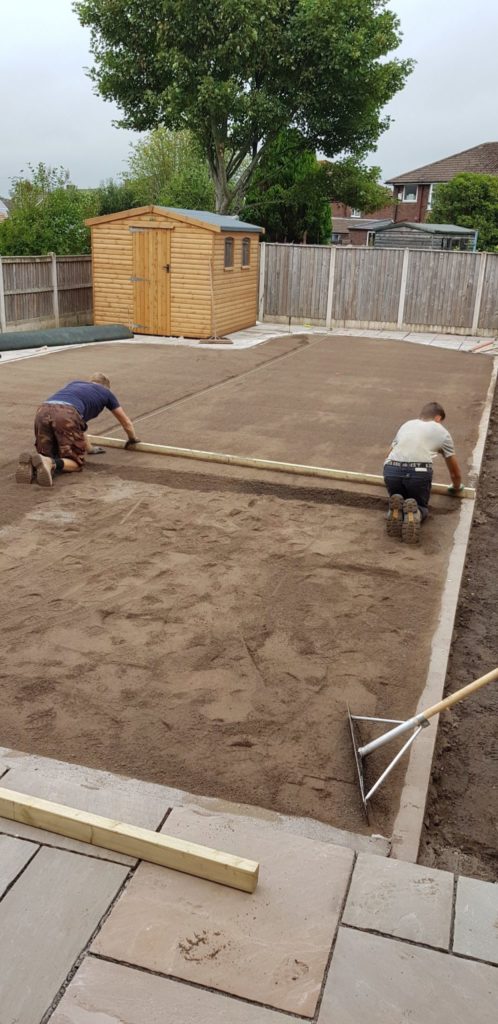 two men kneeling to screed sand