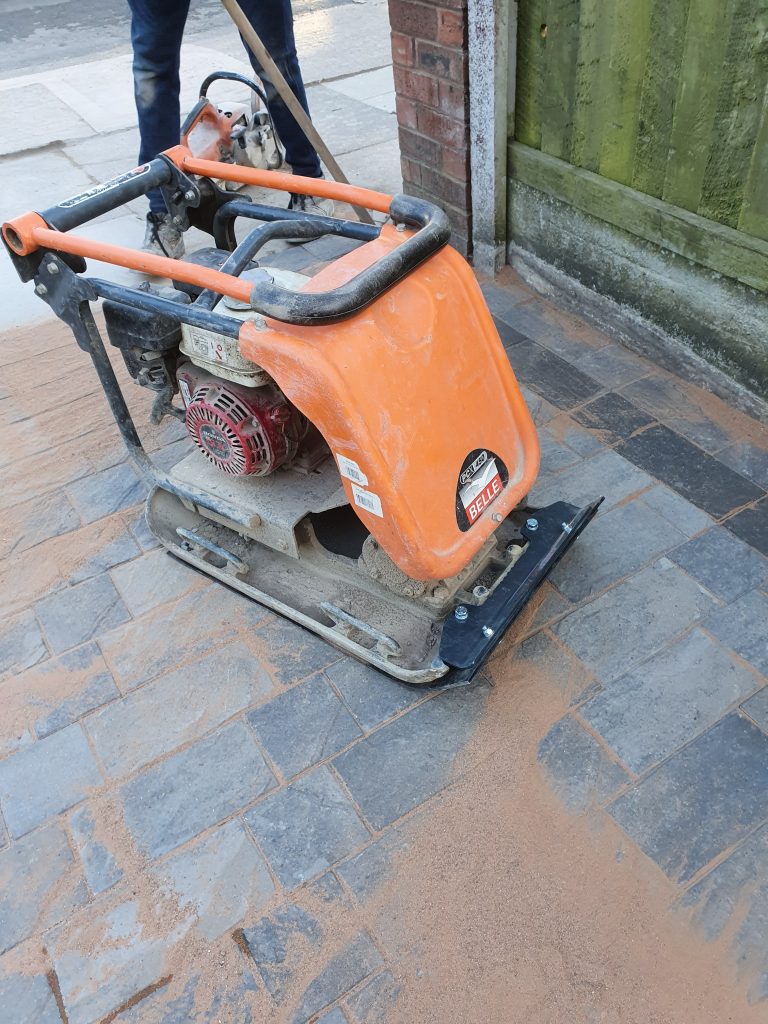 Belle plate compactor with rubber mat used to vibrate block paving into final position