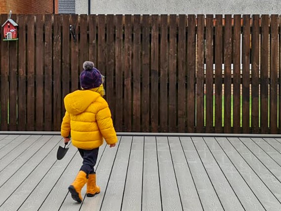 child holding trowel walking on decking